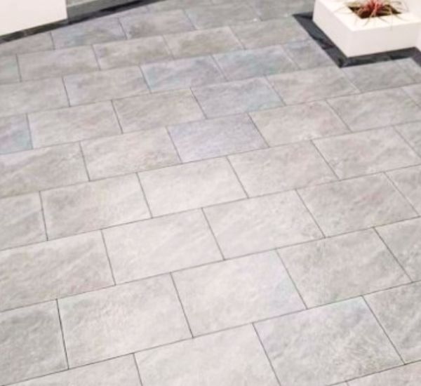 Neatly laid porcelain paving slabs in varying shades of grey, showcasing a modern outdoor flooring design.
